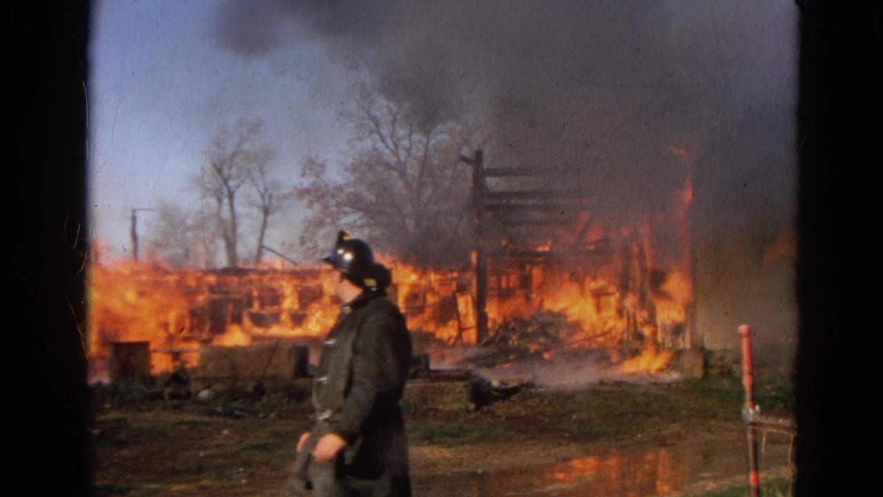 1968 Wauconda, Illinois 8mm frame showing a firefighter moving across the foreground as flames and smoke fill the background.