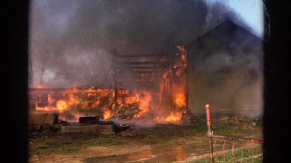 1968 Wauconda, Illinois frame showing flames moving through a farm outbuilding while smoke obscures the roofline.