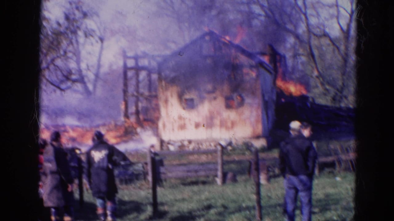 1968 Wauconda 8mm frame showing a barn burning behind a fence as firefighters and onlookers watch from grass.