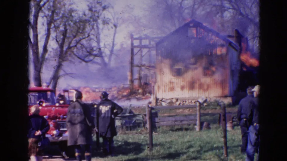 1968 Wauconda frame with a red fire truck near firefighters and onlookers as a barn burns in smoke.