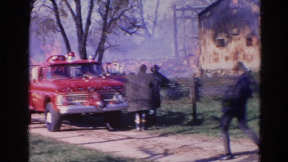 1968 rural fire response with a red fire truck, bystanders, smoke, and a burning wooden structure in Wauconda, Illinois.