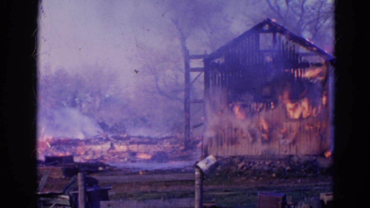 Burning wooden shed with flames and smoke behind dark vertical frame borders.