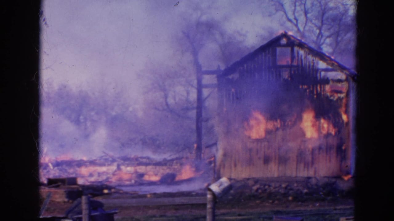 Flames burn through the side of a wooden outbuilding with smoke behind it.