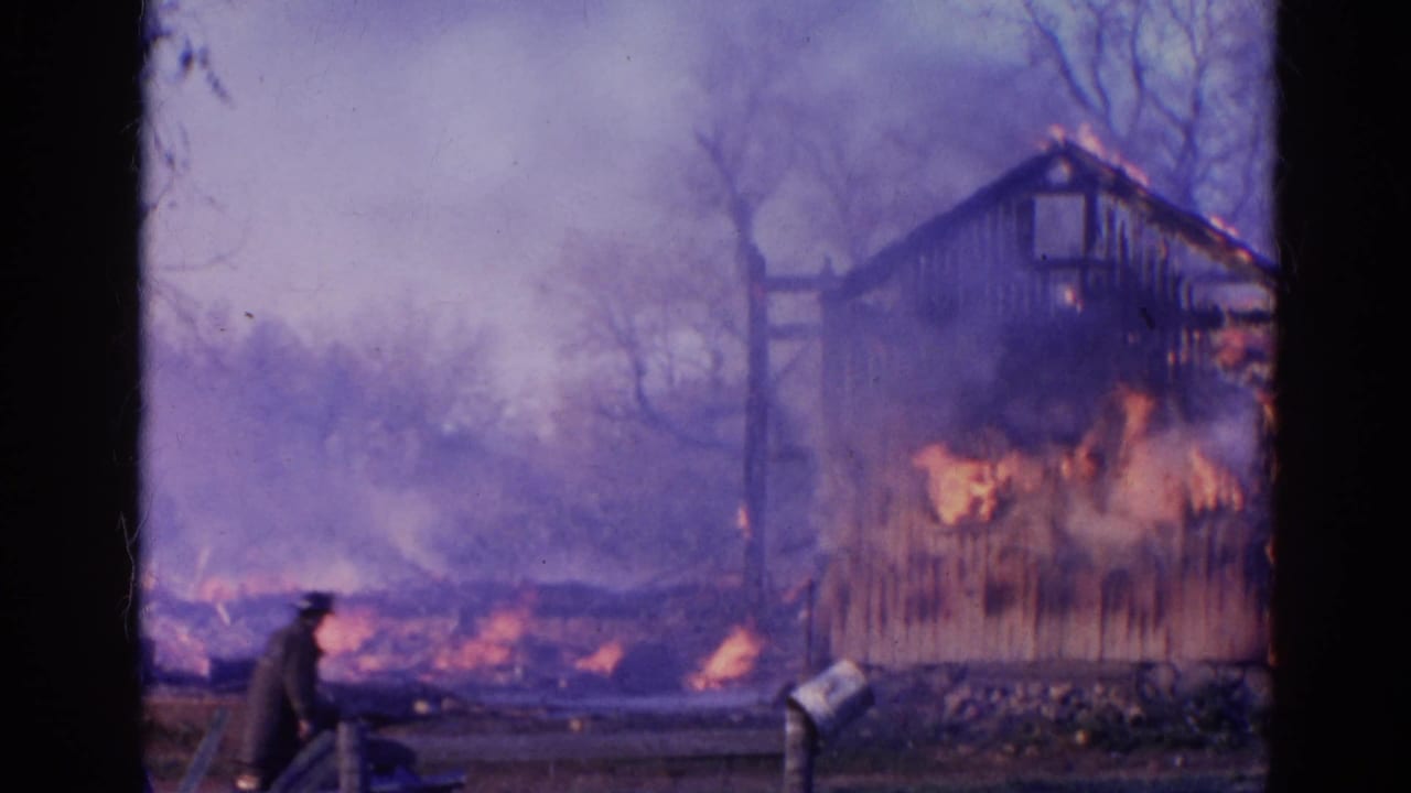 A person in dark clothing appears near the foreground as the burning wooden shed sends smoke across the Wauconda yard.
