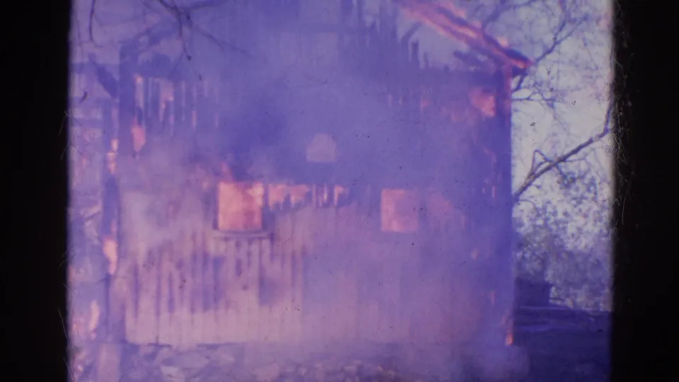 1968 Wauconda, Illinois 8mm frame showing a smoke-covered wooden structure with fire visible inside and along the wall.