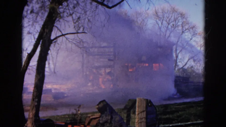 The Wauconda fire scene continues with smoke spreading across a burning frame structure in a wooded setting.