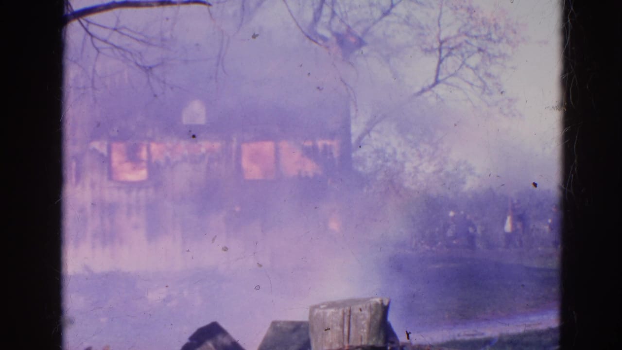A 1968 home-movie frame shows the house fire muted by dense smoke, with fence posts and bare trees visible nearby.