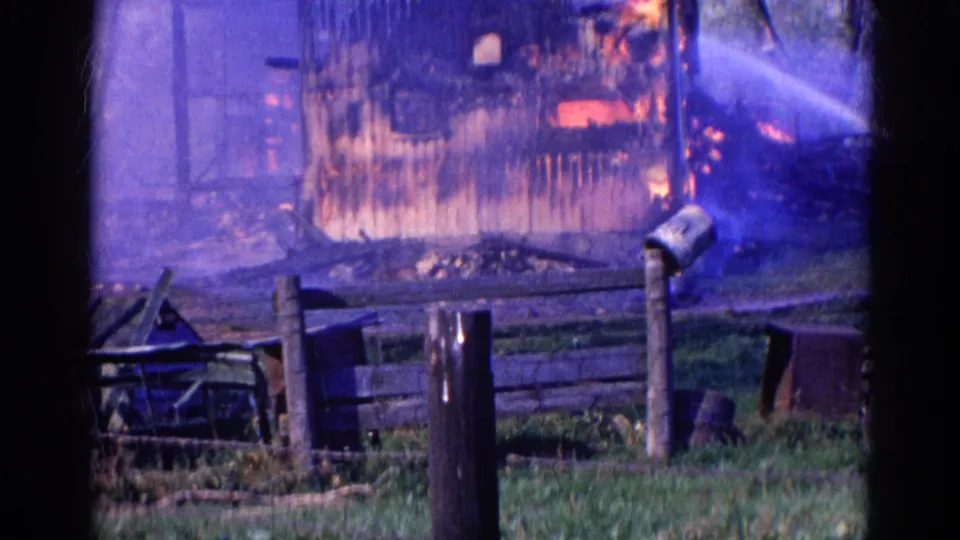 Wauconda, Illinois structure fire with water spray crossing smoke and flames in 1968 home-movie footage.