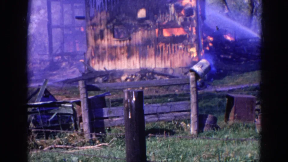 8mm frame of a Wauconda rural structure fire, with flames inside the wall and water spray from the right.