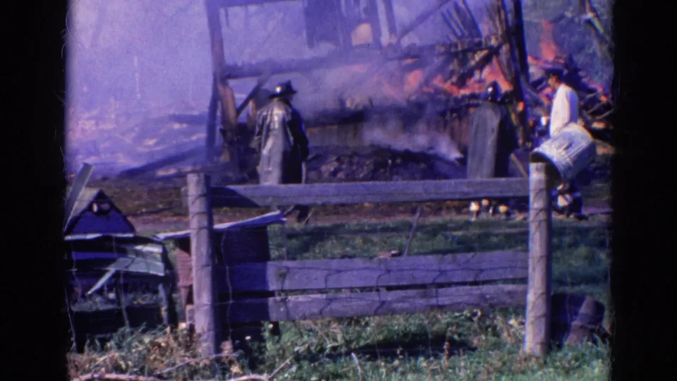Firefighters in period coats stand near flames and smoke at a damaged wooden structure in Wauconda, Illinois, according to clip metadata.