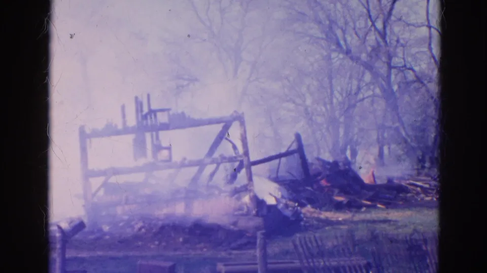 1968 Wauconda 8mm view of a partially collapsed burned structure with smoke and scorched debris.