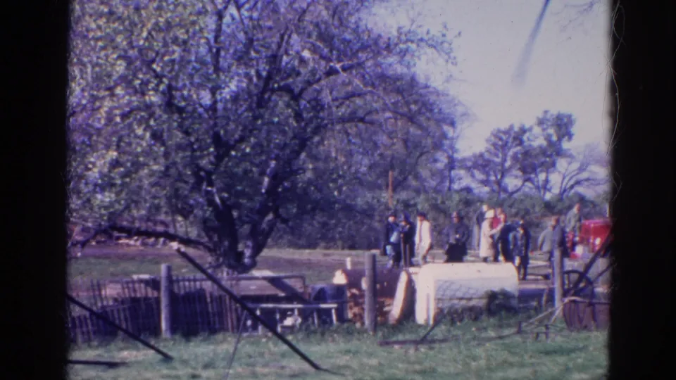 Adults gather in a Wauconda yard in 1968, with trees, fencing, and a red tractor-like vehicle nearby.