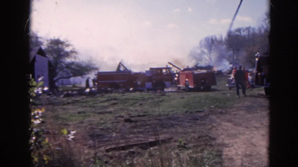 Final frame shows red fire engines, smoke behind trees, people near the field edge, and rural structures in 1968 Wauconda, Illinois.