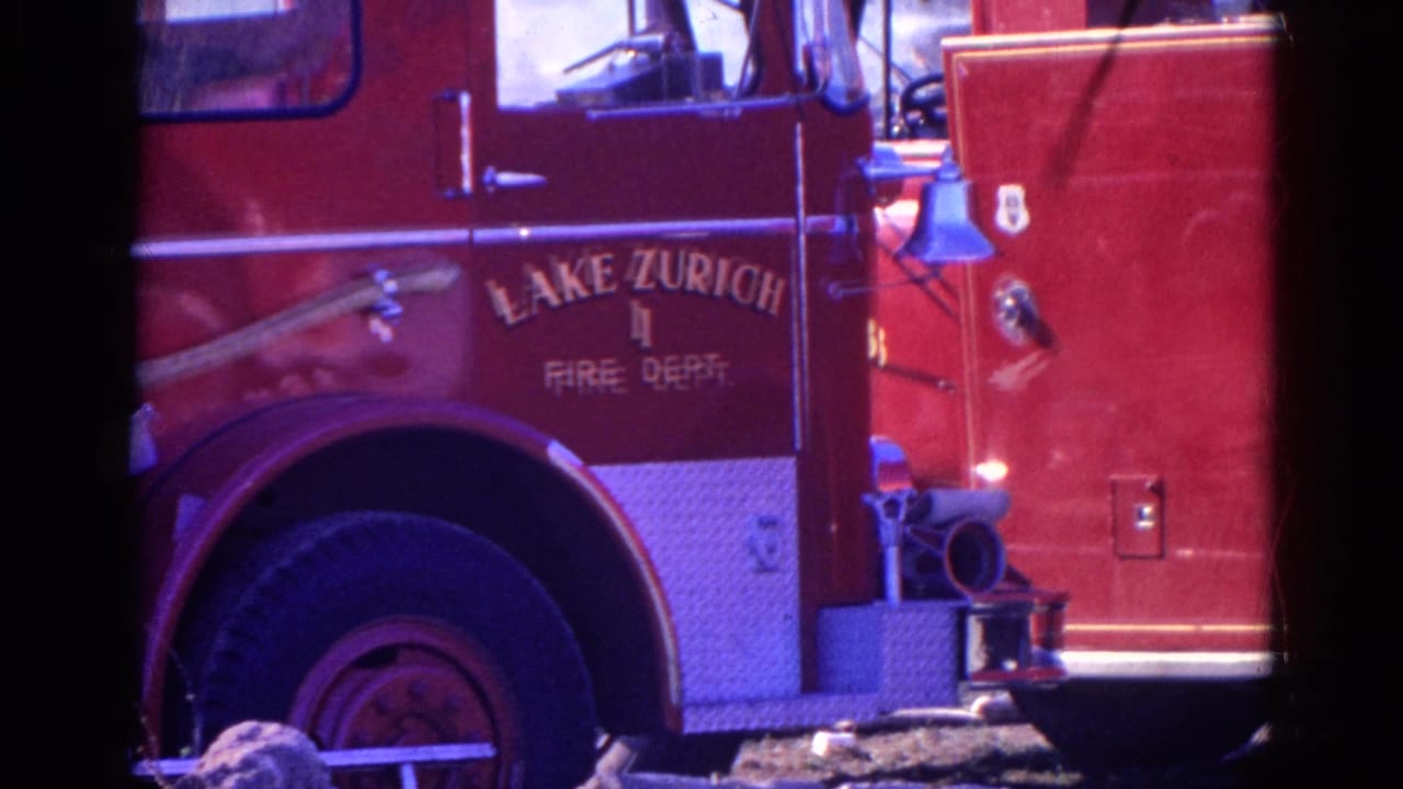 1968 Wauconda-area 8mm frame showing the side of a red Lake Zurich Fire Dept. truck with wheel, hose hardware, bell, and painted lettering.