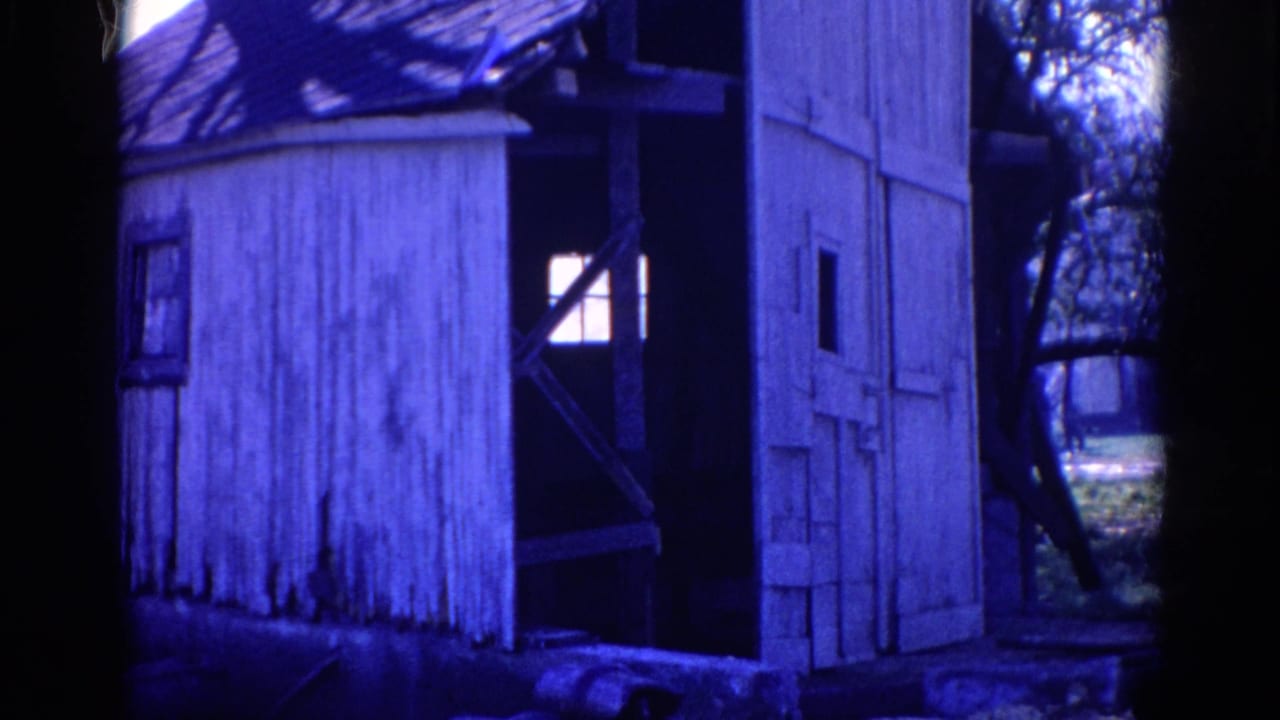 1968 Wauconda 8mm frame showing a weathered white wooden shack partly obscured by dark trees and blue color shift.