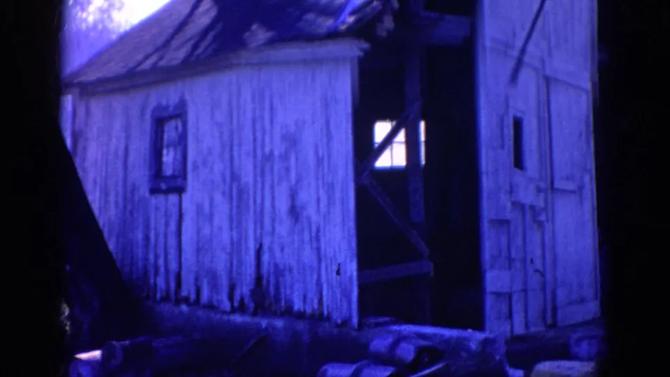 Close 1968 Wauconda 8mm view of the weathered shack wall, small window, rough boards, and shadowed trees.