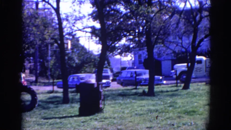 Wauconda, Illinois park footage from 1968 with grass, trees, classic cars, and a white truck along the road beyond.
