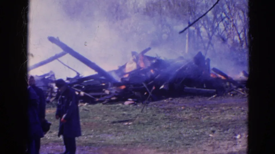 A firefighter remains near the smoldering structure debris in this 1968 Wauconda, Illinois 8mm frame.