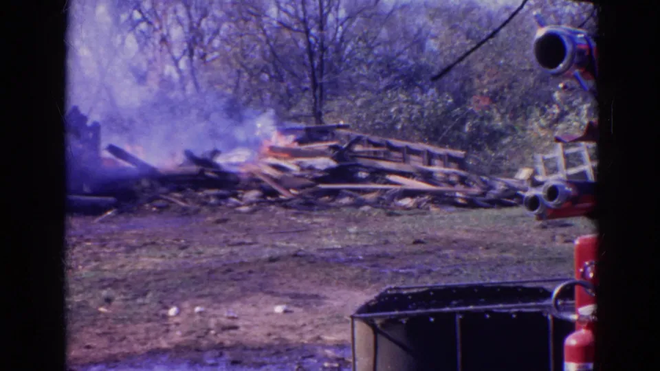 1968 Wauconda, Illinois frame showing a smoky debris fire with red fire truck equipment entering the right side.