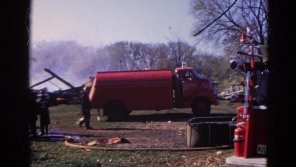 Red Nunda Rural fire truck in a 1968 Illinois home-movie scene, with people, smoke, hose lines, and firefighting gear visible.