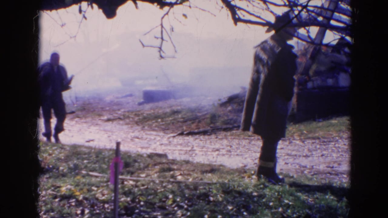 Two men stand near a smoky muddy area, one farther left and one in a long coat near the right edge.