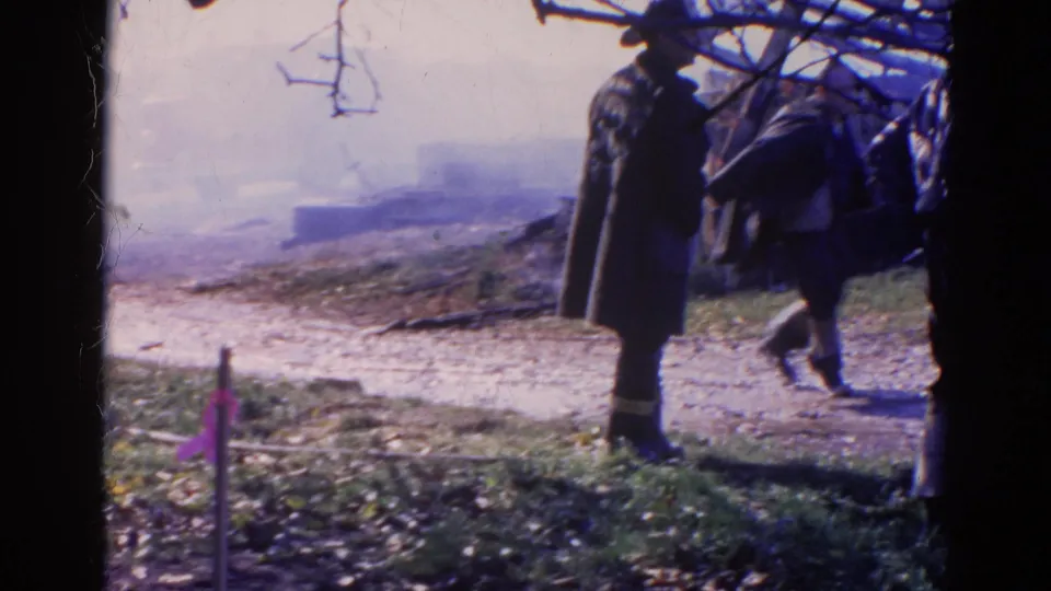 1968 Wauconda, Illinois frame showing a coat-carrying man leaving the scene while another man stands near smoky debris.