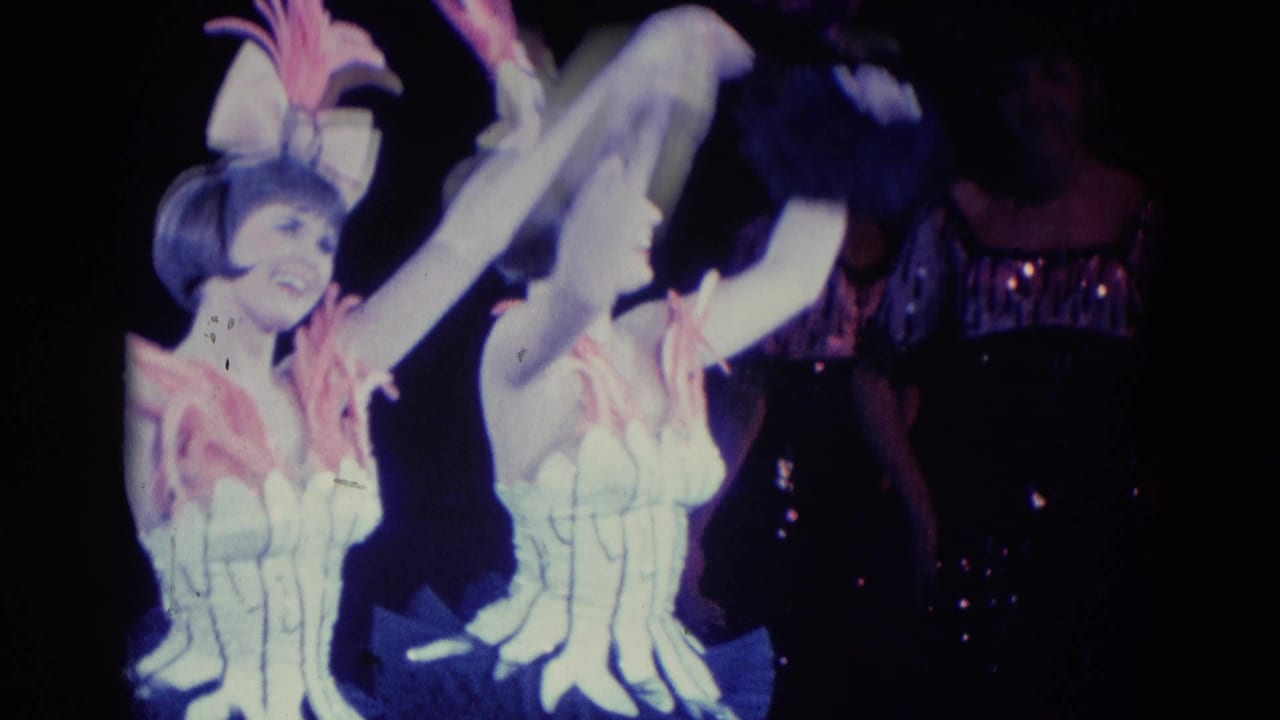 Two female performers in matching white and pink stage costumes raise their arms during a 1969 Chicago 8mm performance moment.