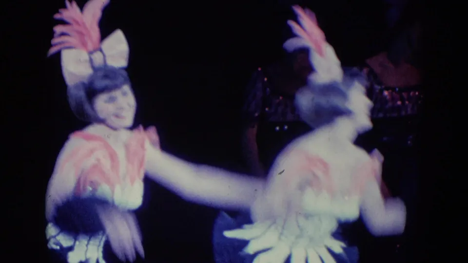 A woman in a feathered stage costume extends her arm as another matching performer passes in blurred motion in this 1969 Chicago clip.