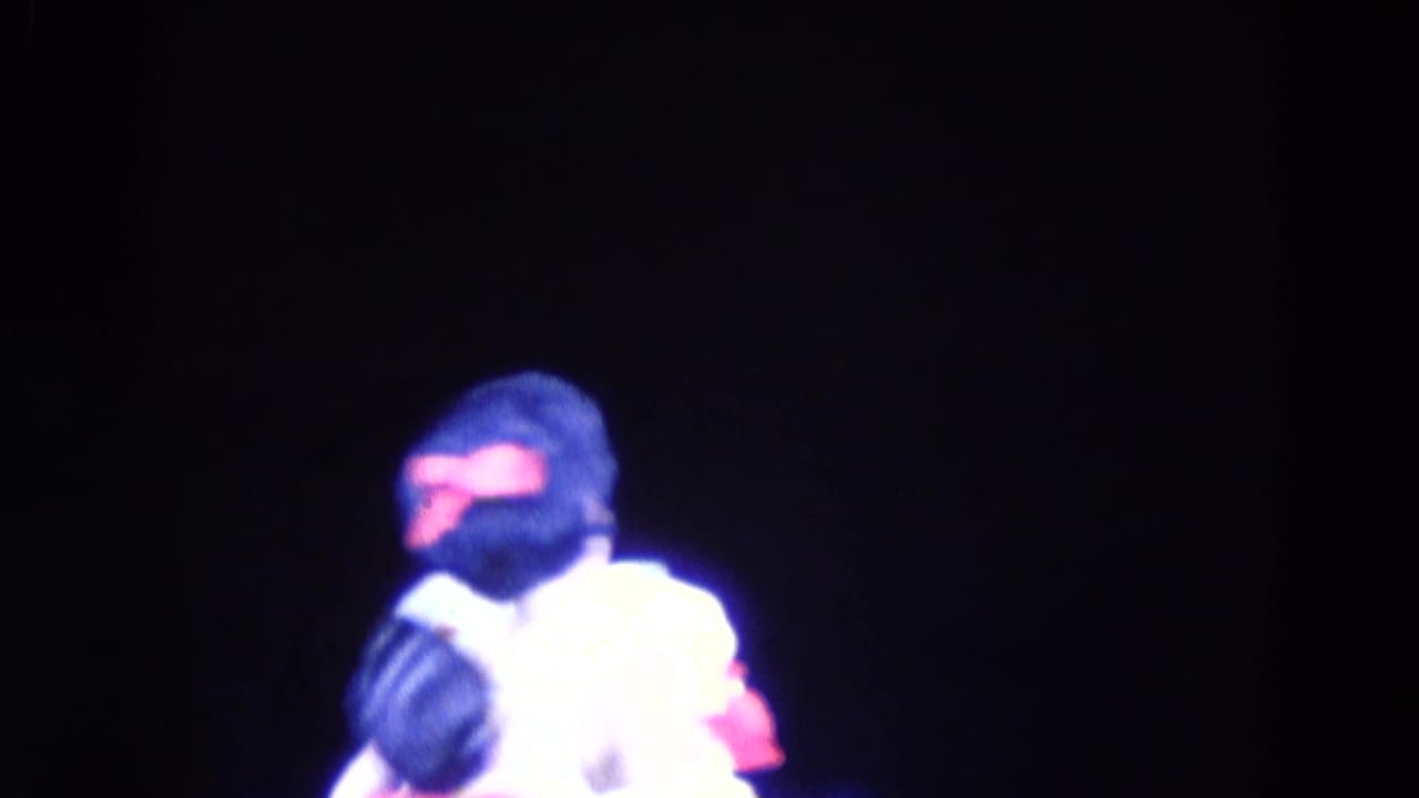 Two skaters under bright stage lighting on a dark rink.