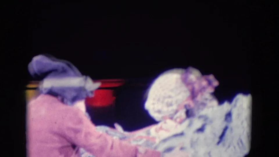 Two costumed performers appear beside the white animal figure on a dim stage, recorded in soft 8mm color footage.