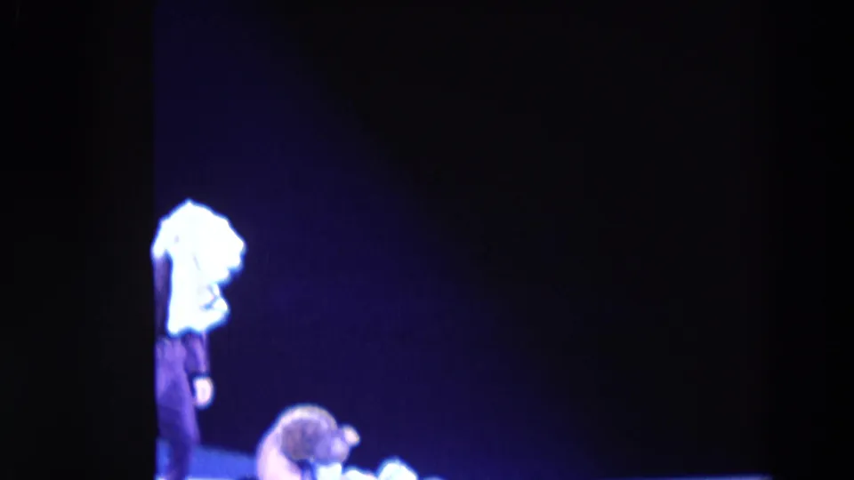 1969 Chicago home-movie frame showing a costumed performer with a bright white headpiece near a crouched skater in low blue light.