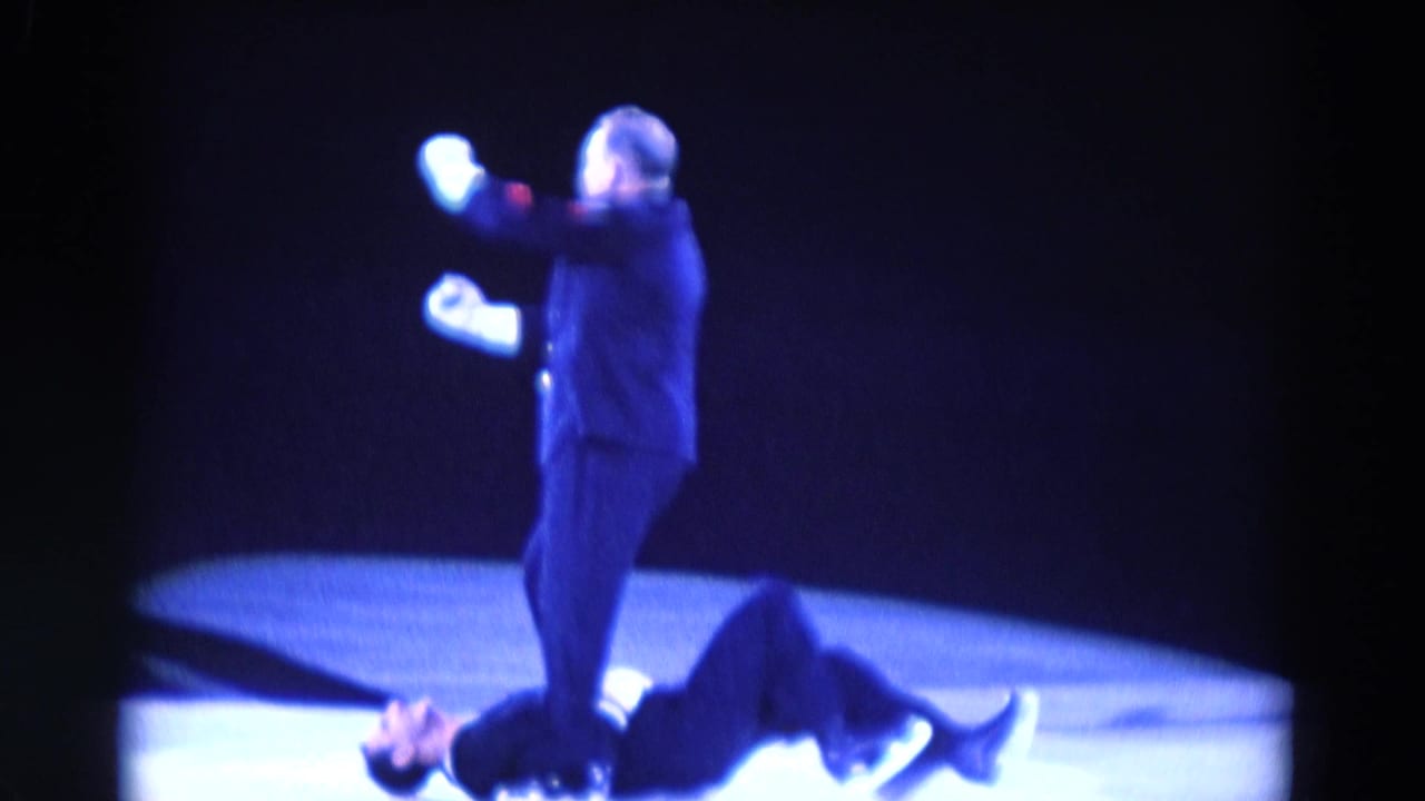 1969 Chicago rink footage shows a dark-suited performer with white gloves standing above another performer under blue stage lighting.