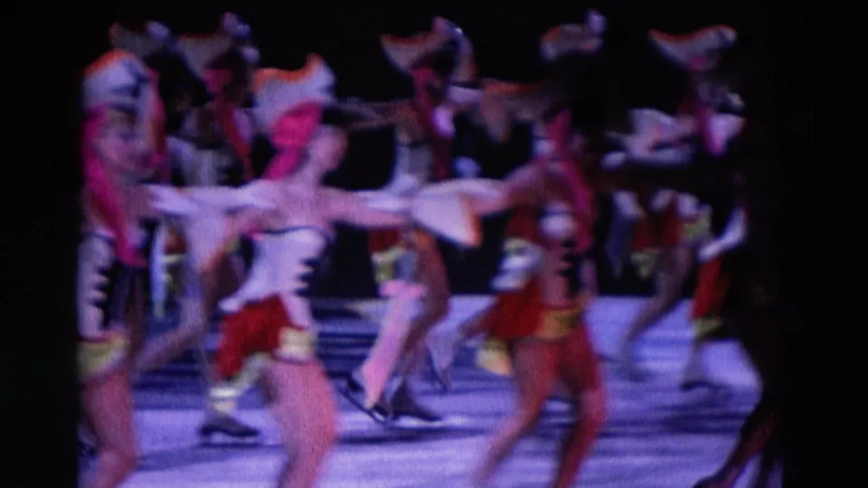 A group of pirate-themed ice-show performers skate with arms extended under dim stage lighting in 1969 Chicago footage.