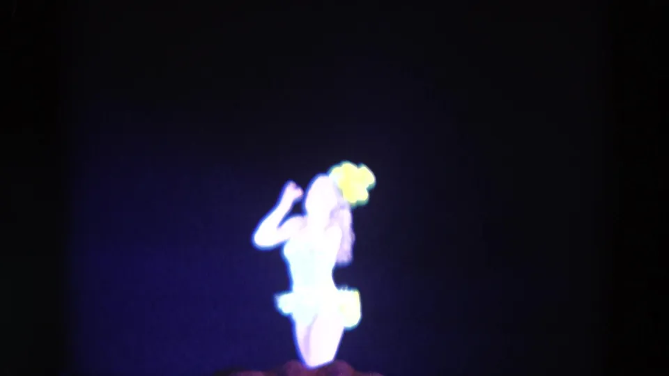 In 1969 Chicago footage, a distant performer in yellow feathers dances against a dark stage backdrop with blue lighting.