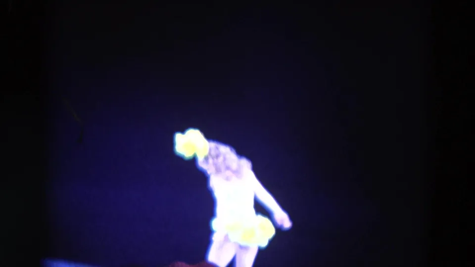 The 1969 Chicago stage performer leans sideways, her yellow costume glowing under blue theatrical light.