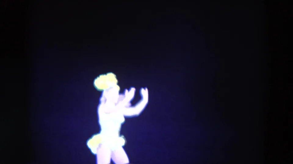 1969 Chicago 8mm frame showing a female figure skater in a bright costume with yellow accents against a dark rink background.
