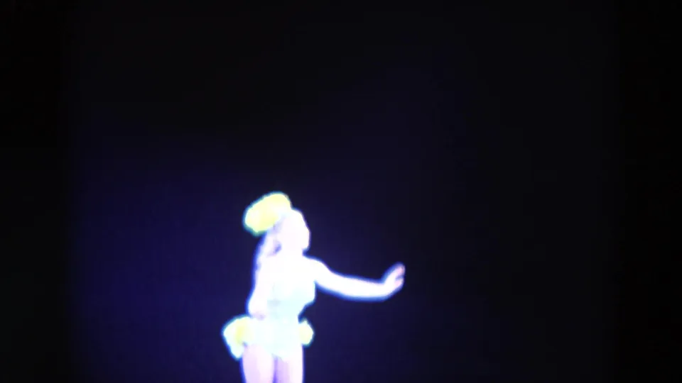 Female figure skater in a light costume and yellow headpiece appears mid-routine in the 1969 Chicago skating footage.