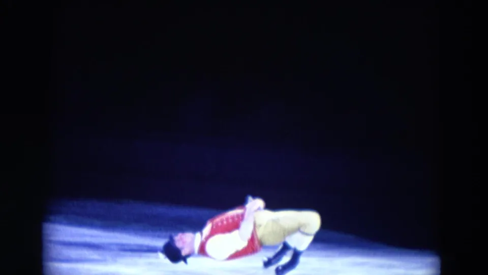 A costumed male ice performer lies back on the rink under stage lighting, part of a dramatic 1969 Chicago home-movie sequence.