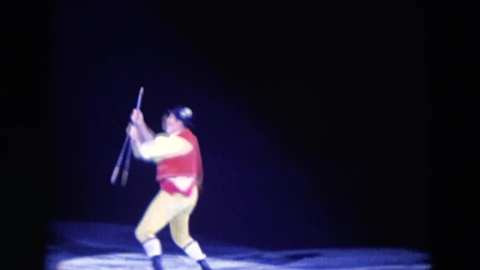 The 1969 Chicago home-movie frame shows the male ice performer upright, holding baton-like props during the routine.