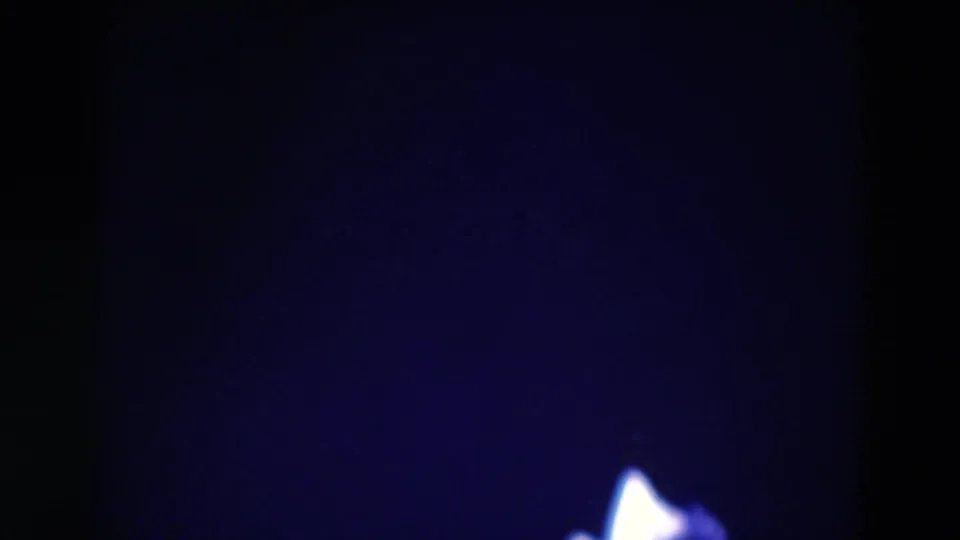 Late-frame 1969 Chicago 8mm view with the dancer mostly out of frame, leaving a dark backdrop and a small bright section of costume near the lower edge.