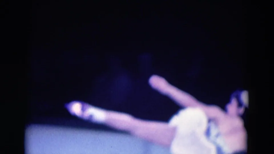 A ballerina in a white tutu raises one leg during a stage movement in the 1969 Chicago ballet footage.