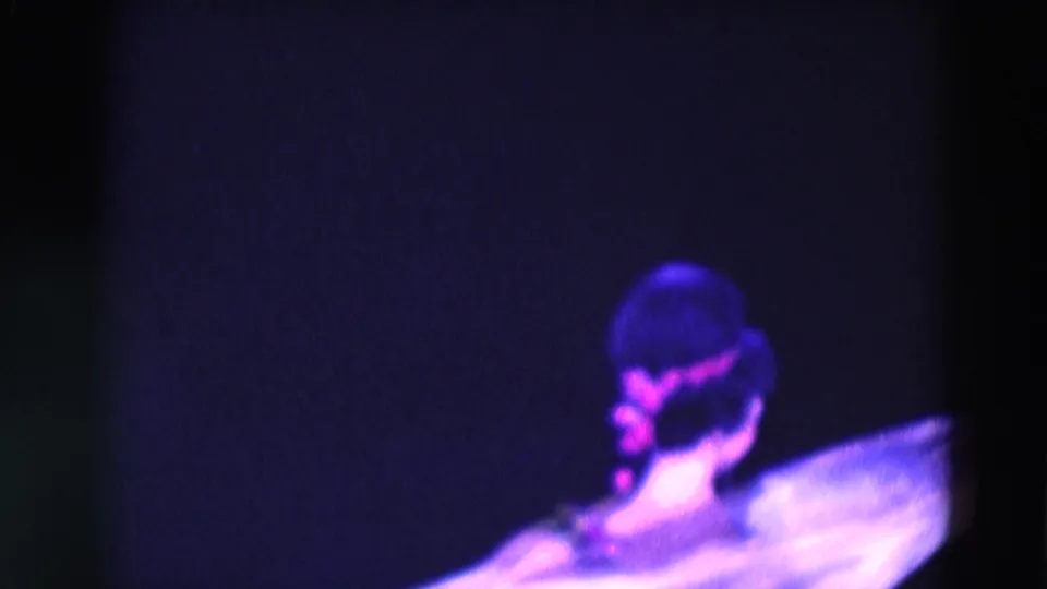 1969 Chicago 8mm frame with a performer seen from behind in a pale gown against a dark stage.