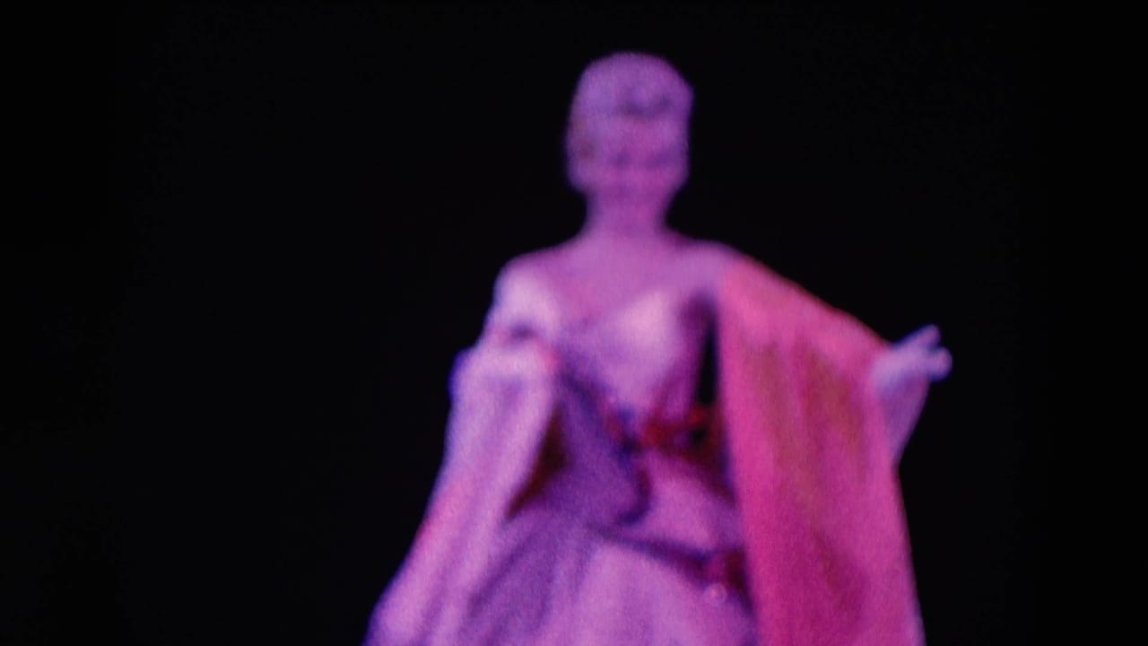 Female stage performer in a glamorous dress under purple-pink lighting.