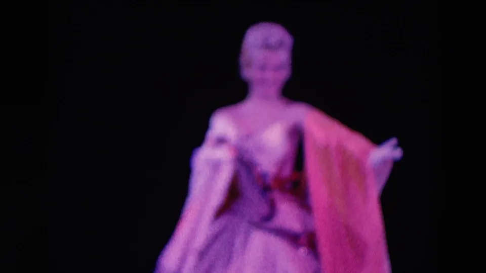 1969 Chicago 8mm frame showing a female stage performer in a glamorous dress against a dark stage background.