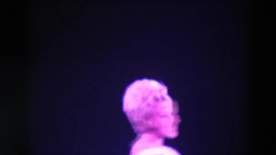1969 Chicago 8mm frame showing the performer in side view, with her face and costume softened by saturated stage lighting.