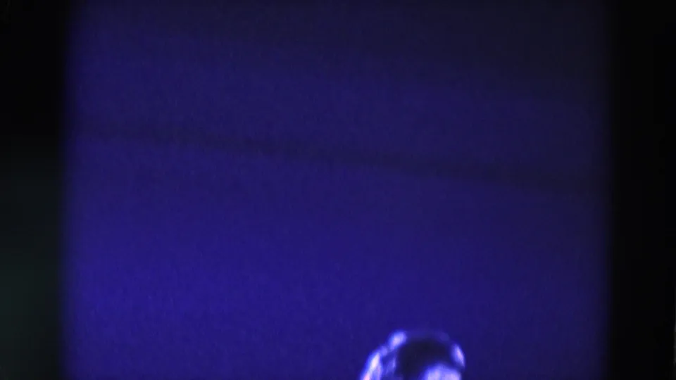 1969 Chicago 8mm frame showing a dark, stage-lit skating space with a small bright portion of the performer at the bottom edge.