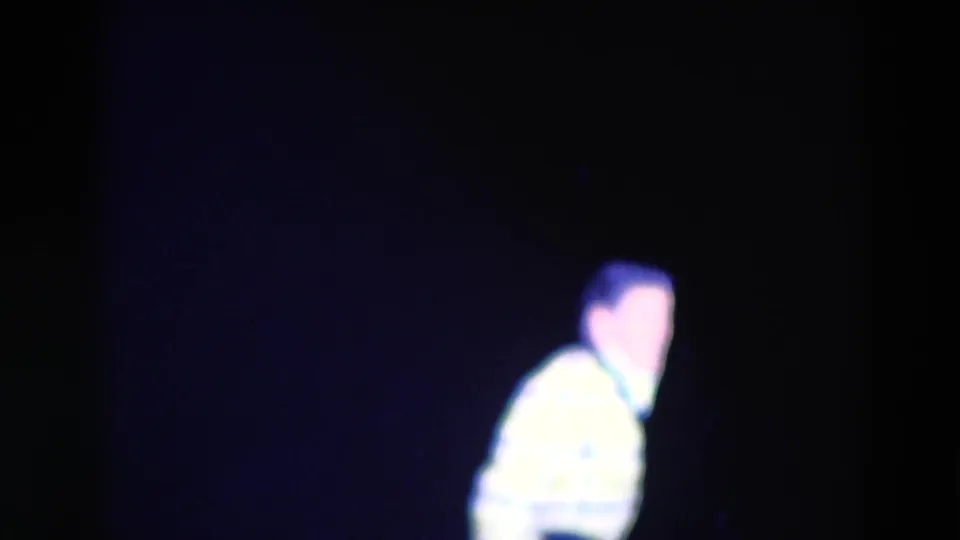 In the 1969 Chicago home-movie footage, a performer in a bright patterned jacket appears in soft focus against a dark stage backdrop.