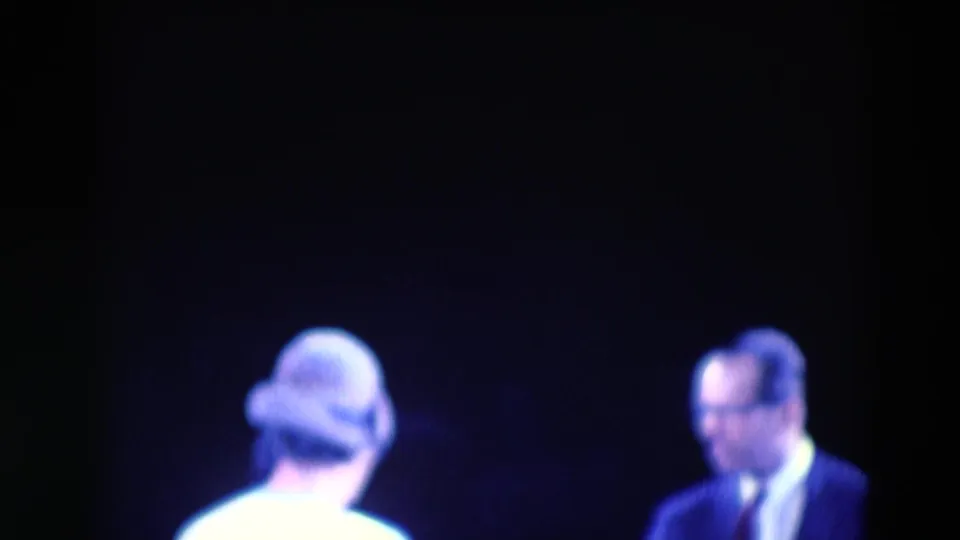 The final frame shows the performer from behind near a suited man, both softly focused within the dark 8mm stage setting.