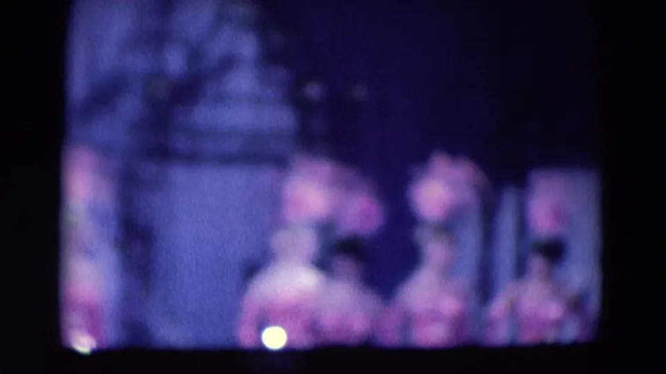 1969 Chicago 8mm frame showing blurred pink-costumed performers on a dark stage, with a central foreground figure.