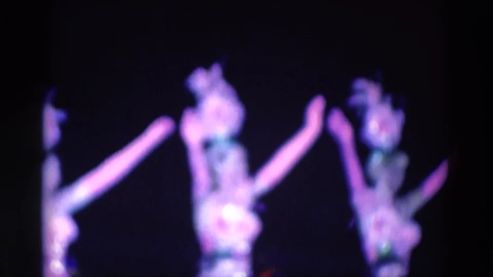 1969 8mm frame showing indistinct dancers in bright costumes under purple stage lights, likely in the Chicago-area clip context.